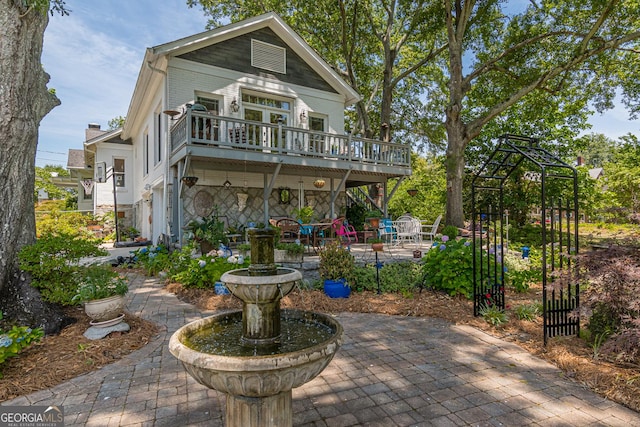 exterior space with a deck, stone siding, and a patio area