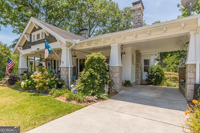 view of front facade with brick siding, concrete driveway, stone siding, a carport, and a chimney