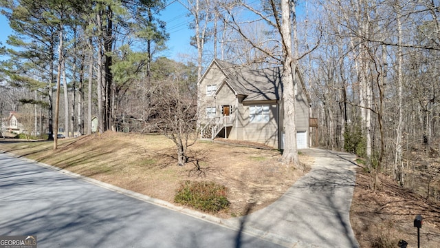 view of yard featuring driveway, an attached garage, and stairs