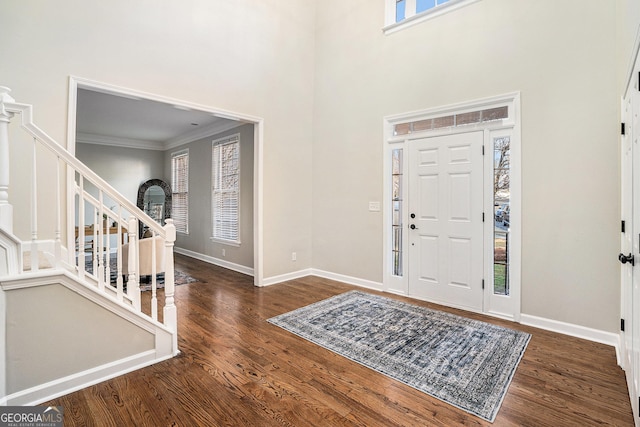 entrance foyer with stairway, plenty of natural light, wood finished floors, and a towering ceiling