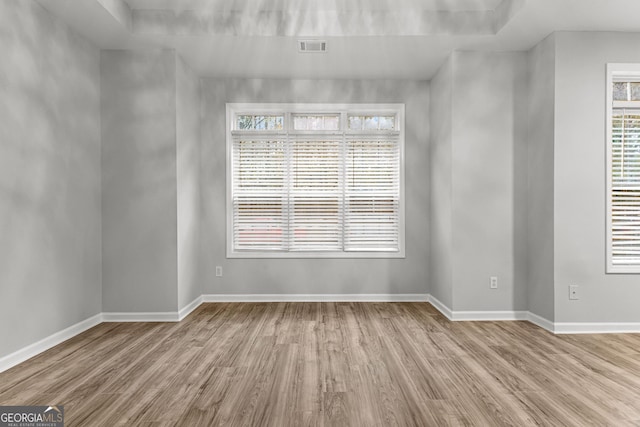 empty room with baseboards, visible vents, and wood finished floors