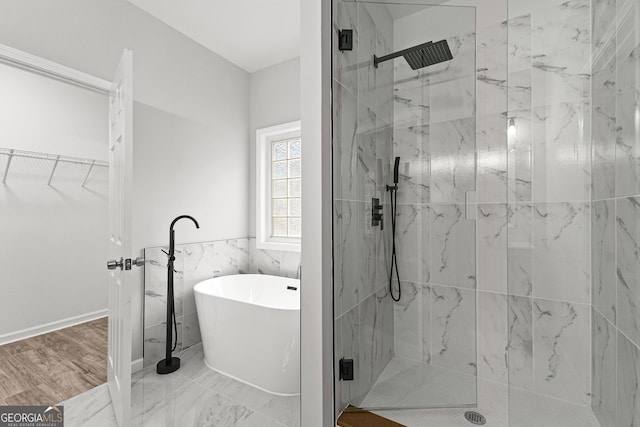 full bath featuring marble finish floor, a marble finish shower, tile walls, and a freestanding bath