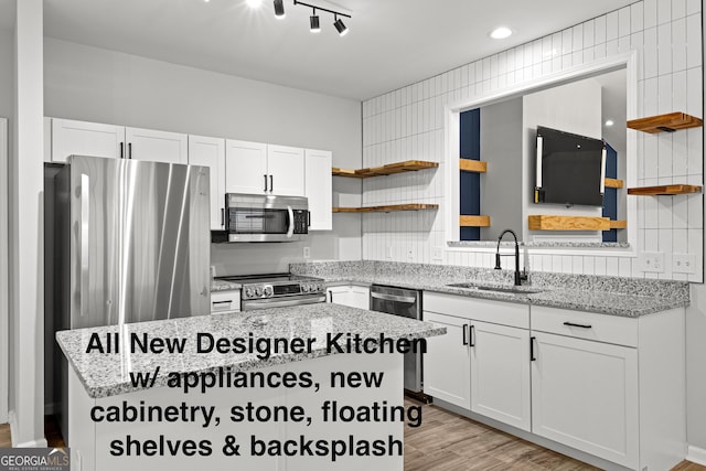 kitchen featuring white cabinets, appliances with stainless steel finishes, a sink, open shelves, and backsplash