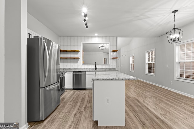 kitchen with open shelves, light wood-style flooring, stainless steel appliances, and a sink