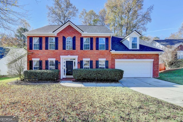 colonial house featuring an attached garage, a front yard, concrete driveway, and brick siding