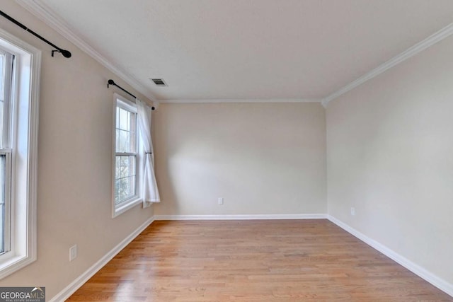 spare room featuring light wood-type flooring, baseboards, visible vents, and crown molding