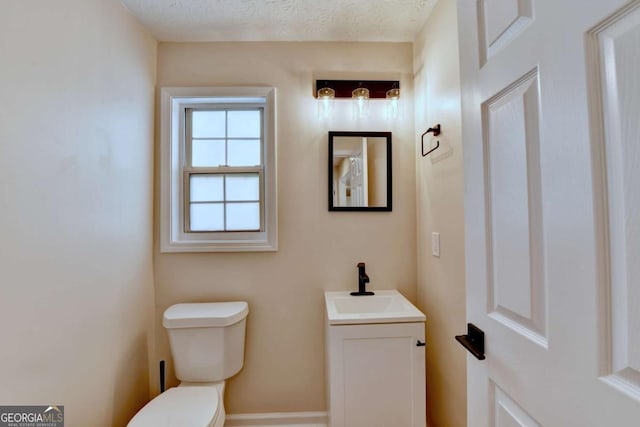 bathroom featuring a textured ceiling, toilet, and vanity