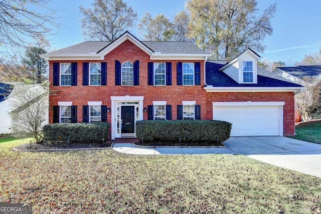 colonial home featuring a garage, a front yard, concrete driveway, and brick siding