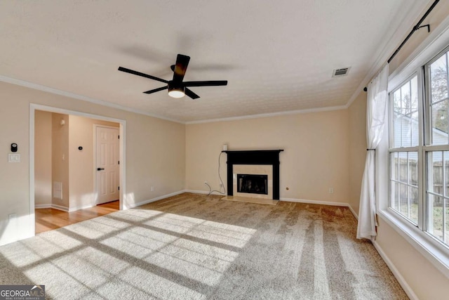 unfurnished living room with baseboards, a fireplace with flush hearth, visible vents, and crown molding