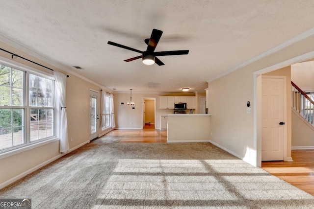 unfurnished living room featuring baseboards, visible vents, stairway, crown molding, and ceiling fan with notable chandelier