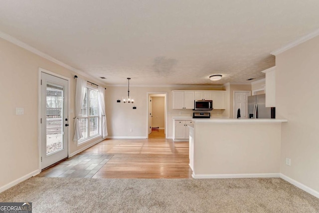 kitchen with baseboards, white cabinets, light colored carpet, ornamental molding, and stainless steel appliances