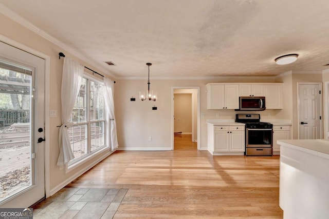 kitchen featuring crown molding, an inviting chandelier, appliances with stainless steel finishes, white cabinetry, and light wood-type flooring