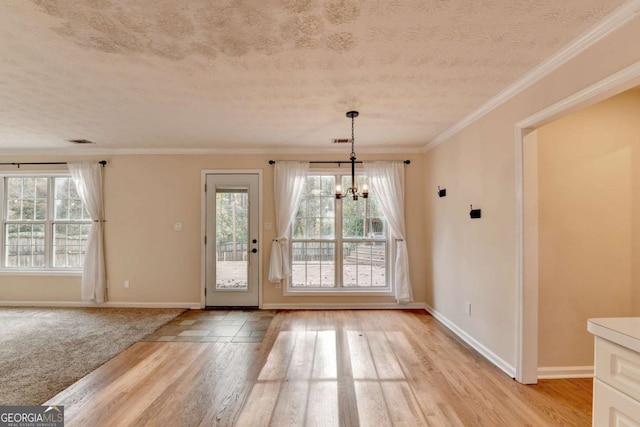 doorway featuring a textured ceiling, an inviting chandelier, a wealth of natural light, and crown molding