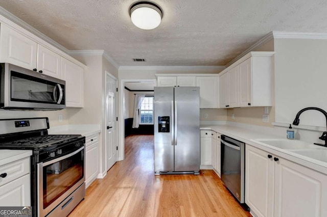 kitchen featuring stainless steel appliances, visible vents, light wood-style flooring, white cabinetry, and a sink