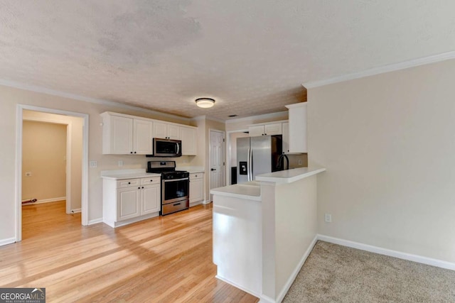 kitchen with stainless steel appliances, light countertops, white cabinetry, a peninsula, and baseboards