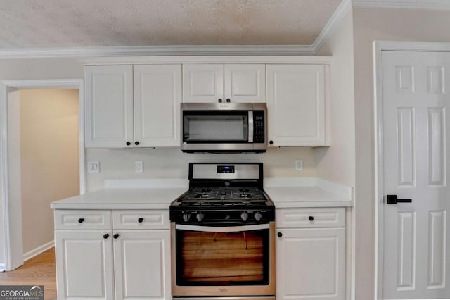 kitchen with light countertops, appliances with stainless steel finishes, ornamental molding, white cabinets, and light wood-type flooring