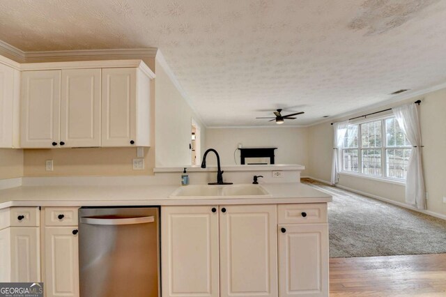 kitchen featuring a textured ceiling, a peninsula, a sink, ornamental molding, and stainless steel dishwasher