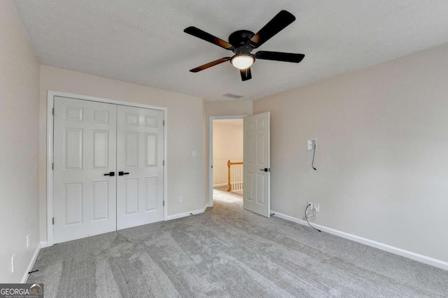 unfurnished bedroom featuring a closet, carpet, a ceiling fan, and baseboards