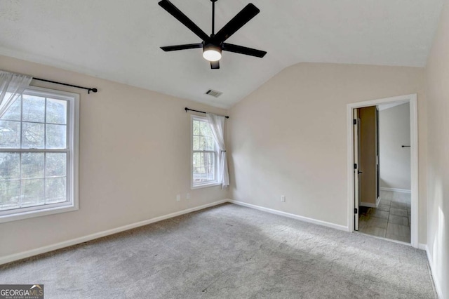 carpeted empty room with a ceiling fan, lofted ceiling, visible vents, and baseboards