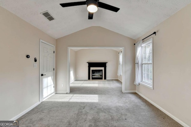 unfurnished living room featuring vaulted ceiling, carpet floors, a fireplace, and visible vents