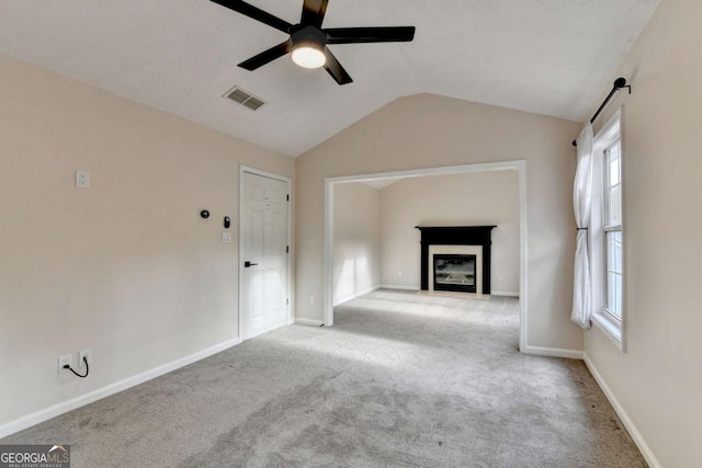 unfurnished living room featuring visible vents, a fireplace with flush hearth, carpet flooring, vaulted ceiling, and baseboards