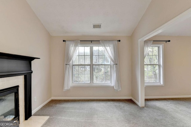 interior space featuring carpet, visible vents, a fireplace with flush hearth, vaulted ceiling, and plenty of natural light