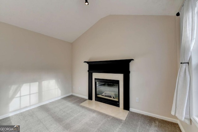 unfurnished living room with carpet, baseboards, vaulted ceiling, and a fireplace with flush hearth