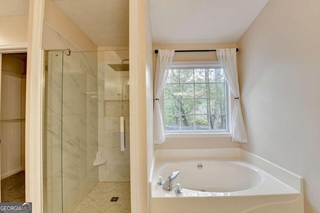 bathroom with a garden tub, a shower stall, and a textured ceiling