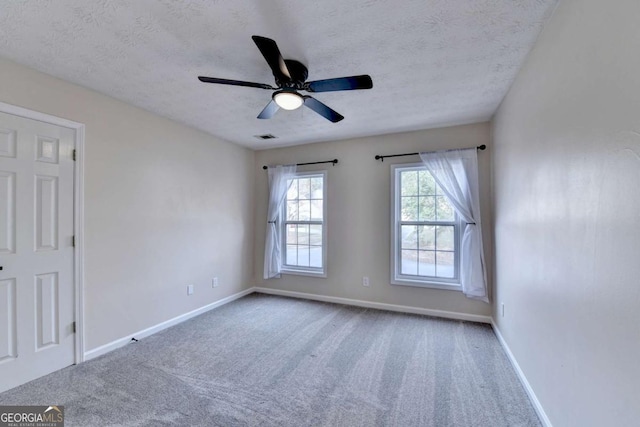 empty room with carpet floors, baseboards, visible vents, and a textured ceiling