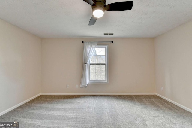 unfurnished room with carpet, visible vents, ceiling fan, a textured ceiling, and baseboards