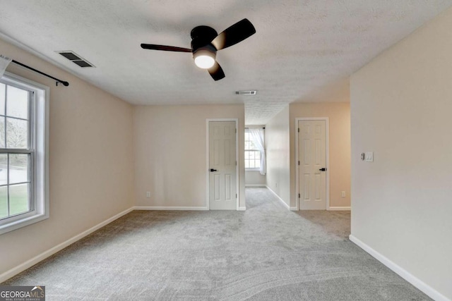 carpeted spare room featuring baseboards, visible vents, and a textured ceiling