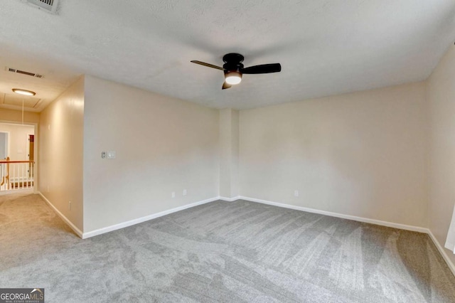 unfurnished room with attic access, visible vents, baseboards, ceiling fan, and carpet floors