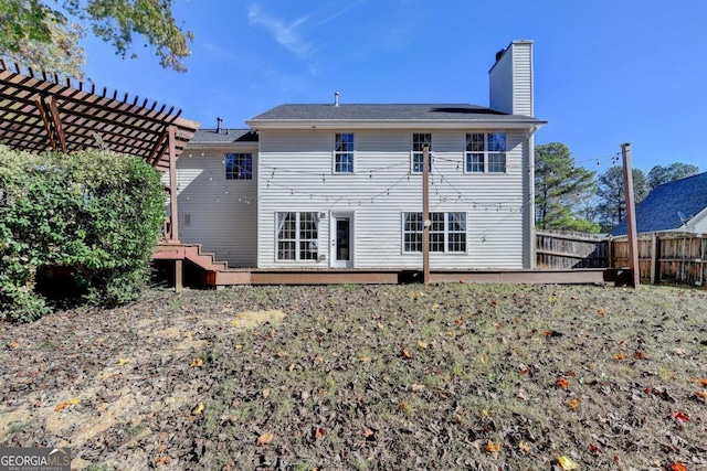 back of house featuring fence, a chimney, a wooden deck, and a pergola