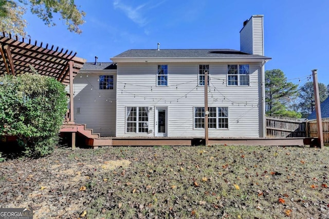 rear view of house with a chimney, fence, a pergola, and a wooden deck