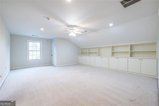 additional living space featuring light carpet, a ceiling fan, visible vents, vaulted ceiling, and baseboards