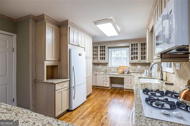 kitchen featuring white appliances, backsplash, light wood-type flooring, and built in study area