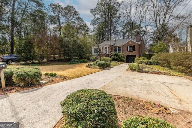 view of front facade with a front yard, concrete driveway, a chimney, and an attached garage