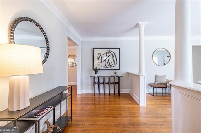 hall with crown molding, decorative columns, baseboards, and wood finished floors