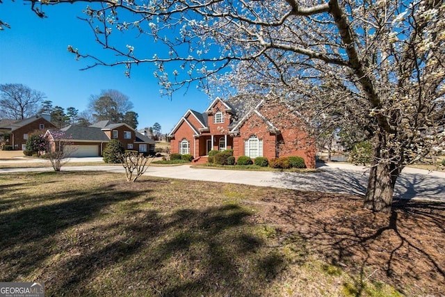 view of front of house with a garage, a front yard, brick siding, and driveway