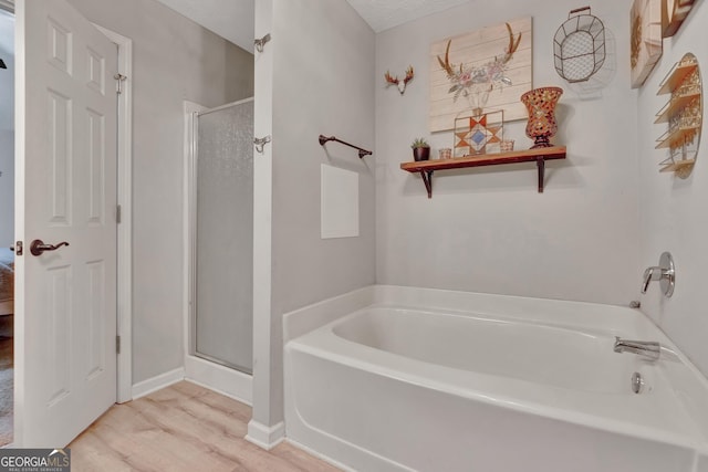 bathroom with wood finished floors, a shower stall, and a bath