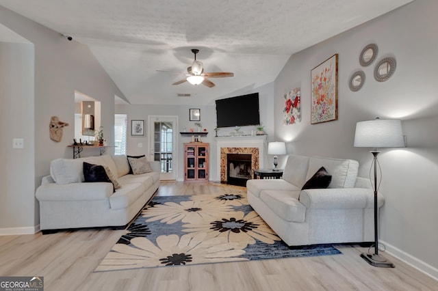 living room with vaulted ceiling, a premium fireplace, baseboards, and light wood-style floors