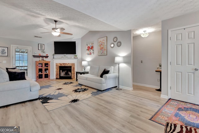 living room featuring a textured ceiling, wood finished floors, visible vents, and lofted ceiling