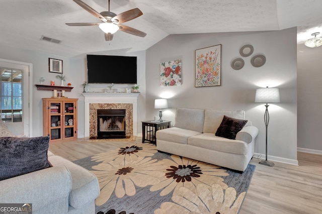 living room featuring light wood-style floors, lofted ceiling, a fireplace, and baseboards