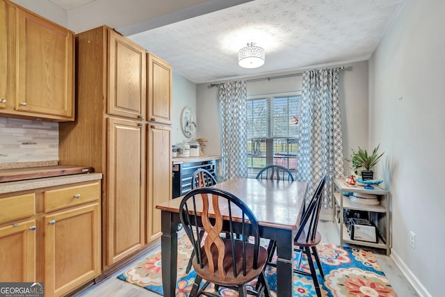 dining room with light wood-type flooring, beverage cooler, baseboards, and a textured ceiling