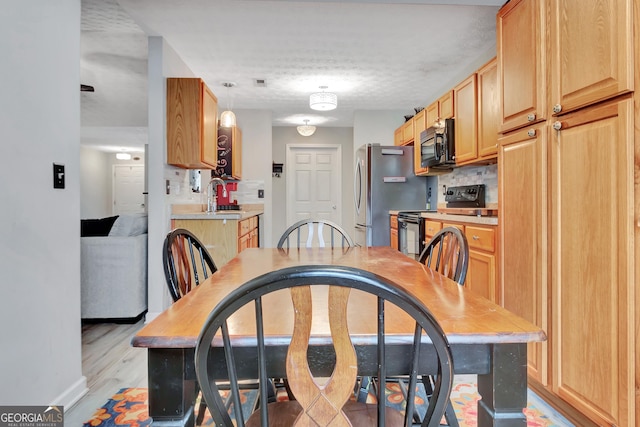 dining area featuring light wood-type flooring, baseboards, visible vents, and a textured ceiling