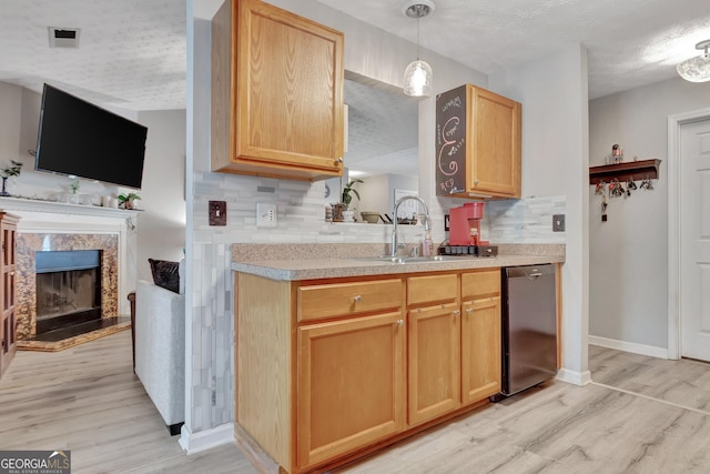 kitchen featuring tasteful backsplash, dishwasher, light wood finished floors, and a sink