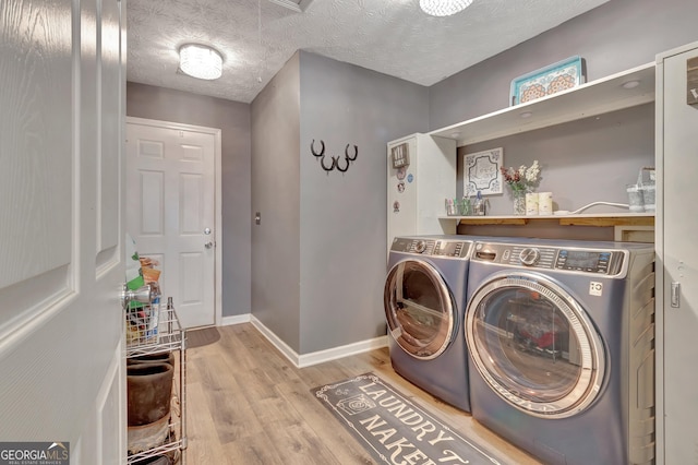 laundry room featuring washing machine and dryer, a textured ceiling, wood finished floors, laundry area, and baseboards