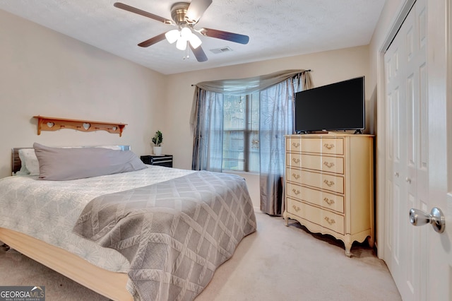 bedroom featuring visible vents, light colored carpet, ceiling fan, a textured ceiling, and a closet