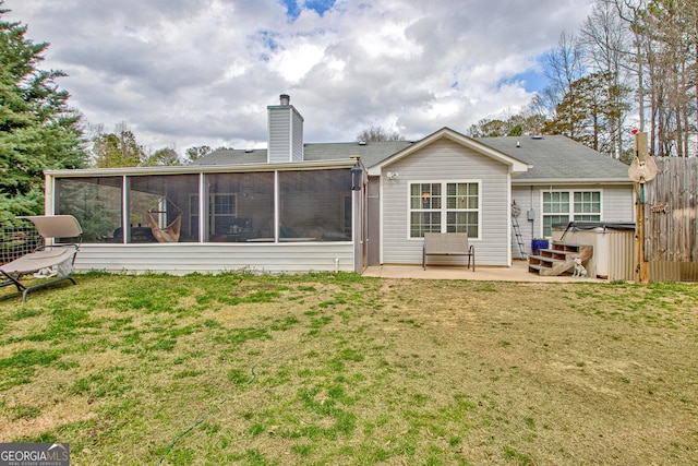 rear view of house featuring a patio, a chimney, a lawn, a hot tub, and a sunroom