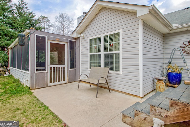 view of exterior entry with a patio area and a chimney